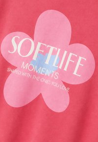 Tissu rose avec un grand motif floral en rose clair et bleu, surmonté d’un texte blanc indiquant « SOFTLIFE MOMENTS SHARED WITH THE ONES YOU LOVE. »