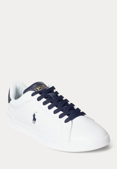 Baskets en cuir blanc avec lacets et languette de talon bleu marine, logo Polo sur le côté et la languette, conçues pour un usage décontracté.