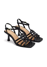 Sandali neri con tacco, caratterizzati da un design con fascia intrecciata, punta quadrata e tacco sottile, con una soletta in pelle liscia.