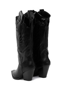 Czarne skórzane kowbojskie buty z wytłoczonymi motywami skrzydeł, zaostrzonymi czubkami i blokowym obcasem. Posiadają zakrzywione krawędzie u góry oraz pętle do łatwego zakładania.