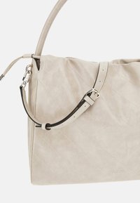 Borsa a tracolla beige trapuntata in pelle sintetica, con una lunga tracolla regolabile e dettagli in metallo argentato.