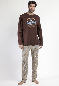 Camisa de manga larga marrón con un gráfico de "Peanuts All Star". Pantalones de pijama beige con un patrón de Snoopy y acentos en azul. Tejido de algodón suave.