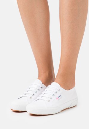 Baskets en toile blanches à design bas, bout rond et cinq œillets pour les lacets. Semelle en caoutchouc texturée et détail de logo subtil sur le côté.