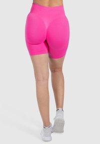 Bermudas de tiro alto en rosa brillante con una textura suave. El diseño presenta un ajuste ceñido al cuerpo y una forma contorneada para un soporte mejorado.
