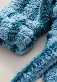 Blauer strukturierter Stoff in verschiedenen Blautönen mit einem flauschigen, zotteligen Aussehen. Das Material sieht weich und einladend aus.