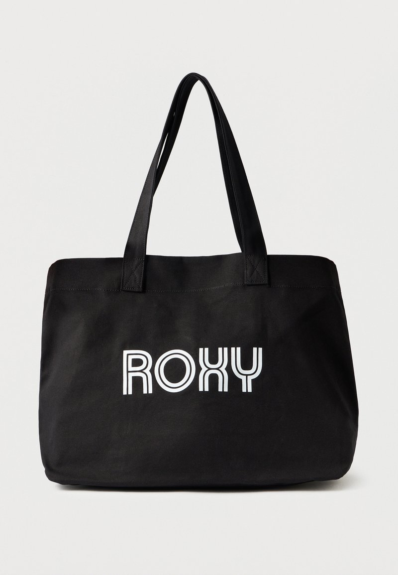 Melna somiņa ar Roxy logo izteiksmīgos baltos burtiem. Tai ir divi rokturi un taisnstūra forma ar gludu auduma tekstūru.
