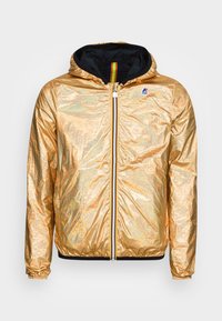 Zlatá lehká bunda s lesklým povrchem, vybavená černou kapucí a kontrastním zipem. Obsahuje logo na hrudi a elastické manžety.