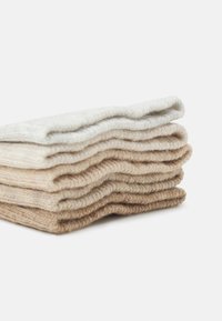 Stapel av garn i neutrala nyanser, inklusive ljusgrå, krämfärg och brunt. Mjuk textur med en lätt fluffig yta. Snyggt vikta lager.