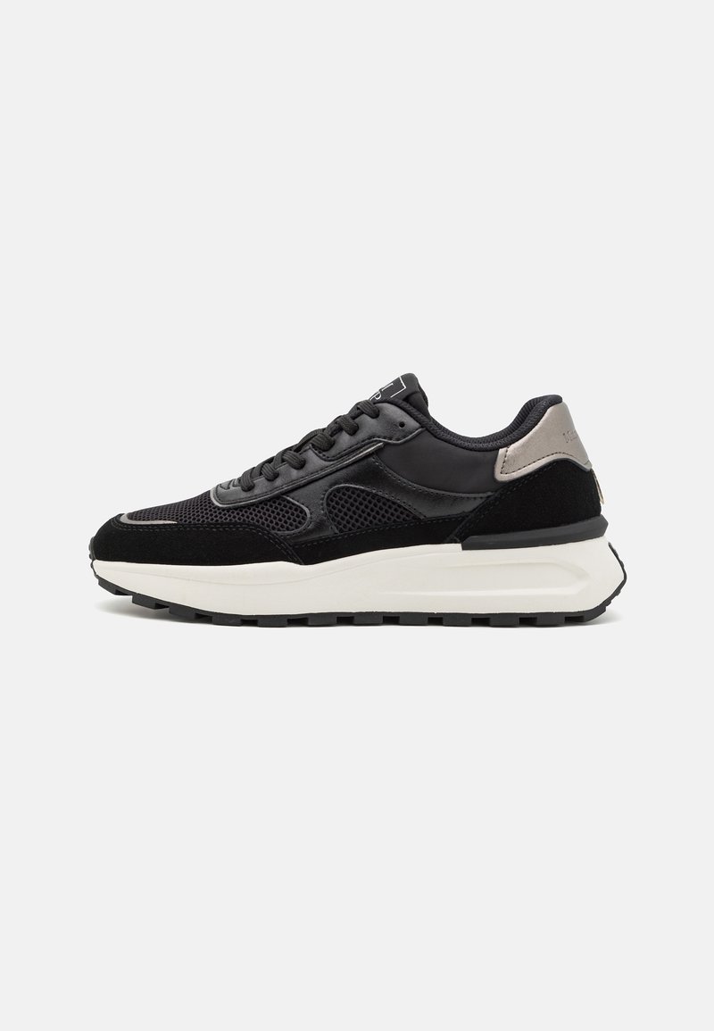 Baskets noires et grises avec panneaux en mesh et daim, semelle blanche épaisse et lacets noirs, montrées de profil sur fond blanc.