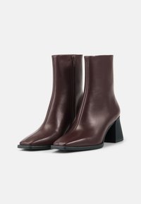 Burgundy leather heeled ankle boots with a pointed toe and side zipper. Block heel and smooth, glossy finish.