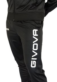 Black athletic tracksuit with a zippered jacket and pants, featuring a shiny material. "GIVOVA" logo in white on the front of the pants.