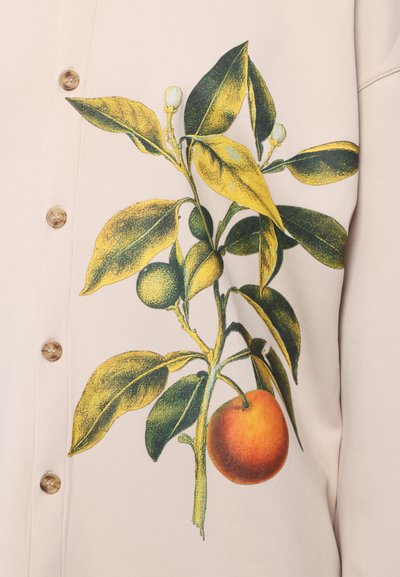 Bežs krekls ar botānisku rakstu, uz kura attēlota dzeltenzaļa citrusu zars ar diviem augļiem, viens ir apelsīns, un vairākiem lapām; pogas sānos.