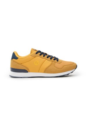 Zapatillas deportivas amarillas con parte superior de ante y malla, acentos en azul marino, suela texturizada y entresuela blanca. Diseño clásico con cordones.