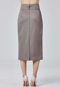 Jupe crayon grise à taille haute, avec une coupe structurée, fente au dos et tissu lisse. Portée avec des chaussures à talons clairs.