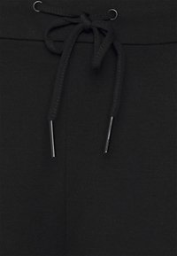 Black sweatpants featuring a drawstring closure with metallic aglets, made of soft fabric with a smooth texture and minimal stitching details.
