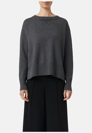 Grauer Strickpullover mit Rundhalsausschnitt, gerippten Bündchen und einem leicht verkürzten, lockeren Schnitt. Kombiniert mit schwarzen weitem Hosen.