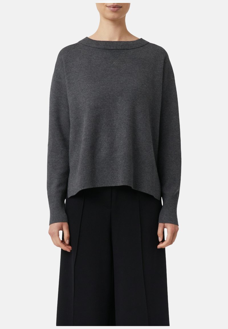 Grauer Strickpullover mit Rundhalsausschnitt, gerippten Bündchen und einem leicht verkürzten, lockeren Schnitt. Kombiniert mit schwarzen weitem Hosen.