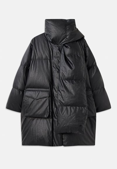 Melna pildīta jaka ar augstu apkakli, lielām kabatām un noņemamu šalli. Izgatavota no spīdīga, tekstūrāta materiāla ar brīvu piegriezumu.