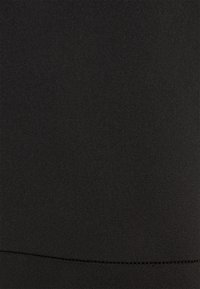 Svart tyg, slät textur, elastisk sträckning, åtsittande design. Har en subtil sömdetalj längs nederkanten. Lämplig för olika stilalternativ.