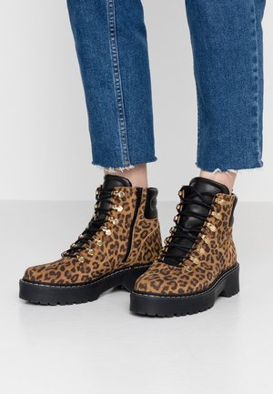 Bottes chelsea à imprimé léopard avec des accents noirs, œillets en métal et semelle épaisse. Finition en suède texturé et design solide à lacets.