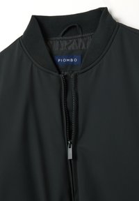 Zwarte bomberjack met een geribde kraag, ritsluiting en logo label. Glad textuur zonder zichtbare patronen of accenten.