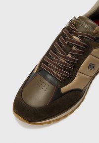 Sneaker in suede marrone e sintetico con dettagli beige, punta tonda, collare imbottito e suola in gomma spessa. Presenta lacci marroni e dettaglio del logo.