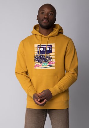 Geel hoodie met een cassettebandje grafiek, verwarde tape en de tekst "Good Old Mess." Zacht materiaal met een zak aan de voorkant en een capuchon met trekkoord.