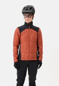 Oranje en zwarte geïsoleerde jas met een hoge kraag, volledige ritssluiting, gepolsterde voorkant en een gestructureerde afwerking. Gemaakt met handschoenen en een bril.