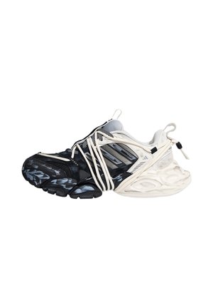 Scarpa da ginnastica bianca e nera con design irregolare, con più lacci bianchi avvolti intorno e una suola spessa isolata su bianco.
