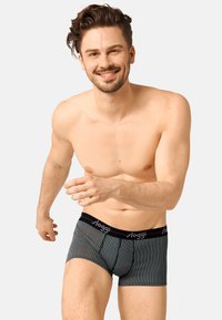 Männer-Unterhosen in Schwarz mit weißen vertikalen Streifen, ausgestattet mit einem roten elastischen Bund, auf dem der Markenname "sloggi" aufgedruckt ist.