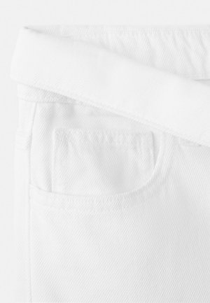 Close-up van het bovenste gedeelte van een witte spijkerbroek met een omgevouwen tailleband en een voorzak met zichtbare stiksels.