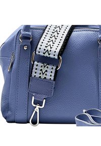 Sac à main en cuir bleu avec une finition texturée, doté d'une bandoulière décorative avec un motif zigzag noir et blanc et des détails en métal argenté.