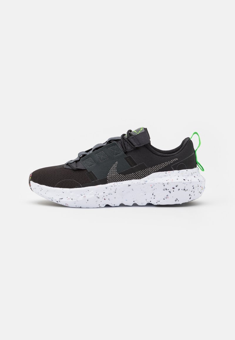 Black athletic shoe with a textured mesh upper, gray accent panels, and a white speckled sole. Features green pull tab and laces.