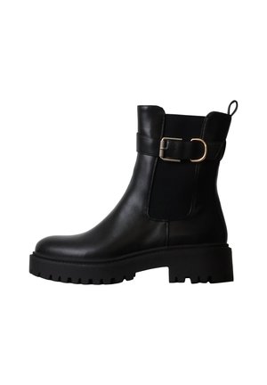 Bottine en cuir noir avec semelle épaisse, panneau élastique latéral, sangle décorative, boucle dorée et languette à l'arrière.