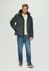 Ciemnoszara kurtka puchowa z kapturem, z zamkiem z przodu i bocznymi kieszeniami, w połączeniu z jasnym swetrem, niebieskimi dżinsami i szarymi butami.