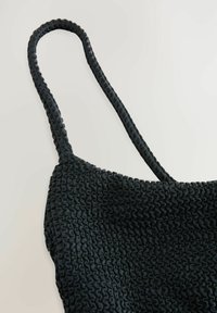 Crni elastični top s teksturiranim, naboranim uzorkom, koji ima tanke naramenice. Materijal je rastezljiv i mekan na dodir.