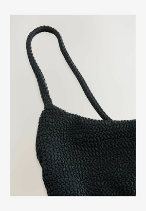 Melns elastīgs topiņš ar teksturētu, saplēstu rakstu, kuram ir plāni siksniņas. Materiāls ir elastīgs un mīksts uz tausti.