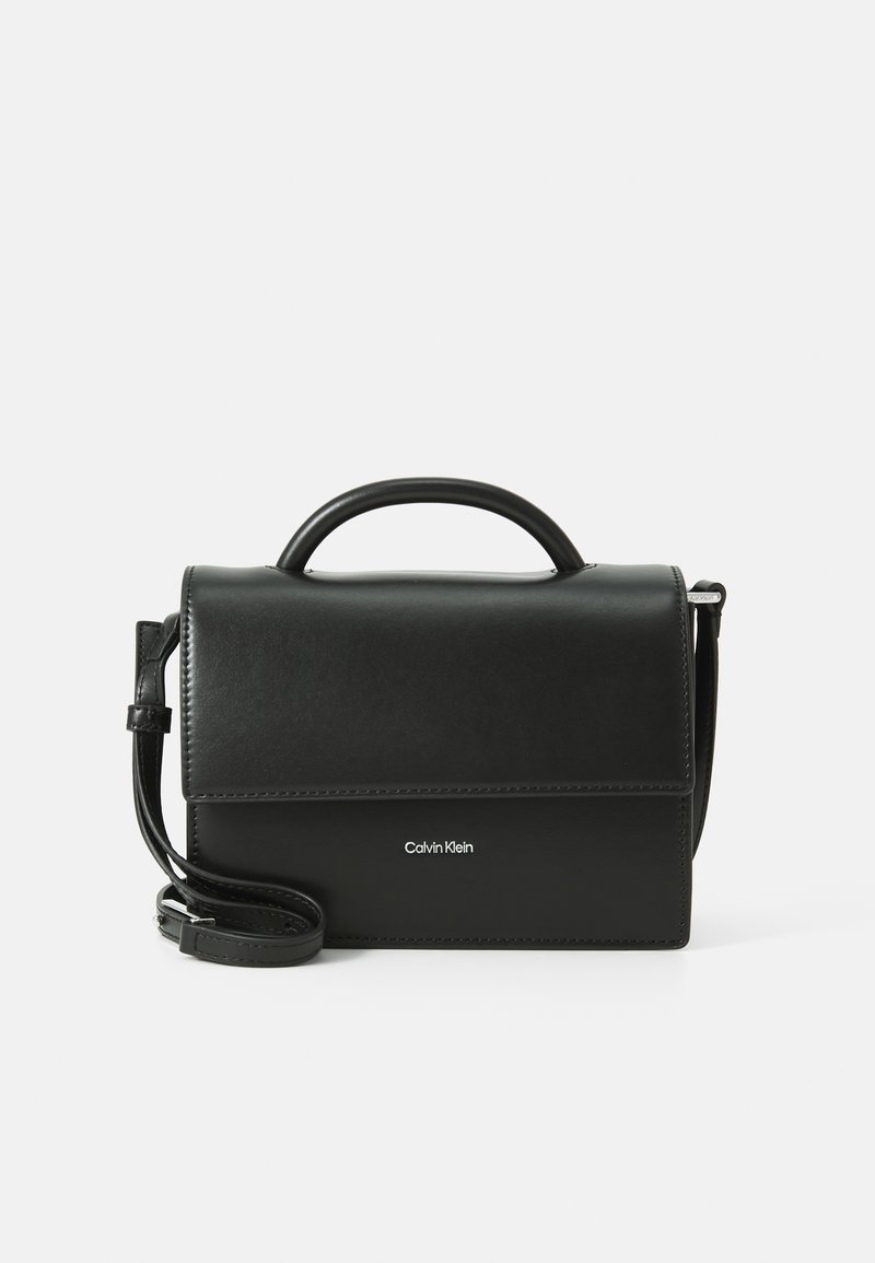 Sac en cuir noir à porter croisé avec une forme structurée, une poignée supérieure et une sangle réglable. Il est doté d'une fermeture à rabat magnétique et d'un détail de logo.