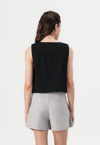 Svartrandig svart kort ärmlös topp med fyrkantig halsringning, matchad med ljusgrå högmidjade shorts, med en ren, slät tygtextur.