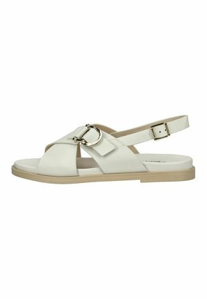 Biała płaska sandałka z szerokimi paskami w kształcie krzyża, srebrną okrągłą klamrą, paskiem na kostkę z regulowaną złotą klamrą oraz beżową podeszwą.