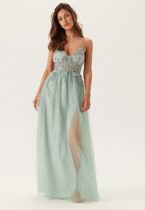 Light teal evening gown with a plunging neckline, floral lace bodice, and sheer skirt featuring a thigh-high slit. Spaghetti straps.