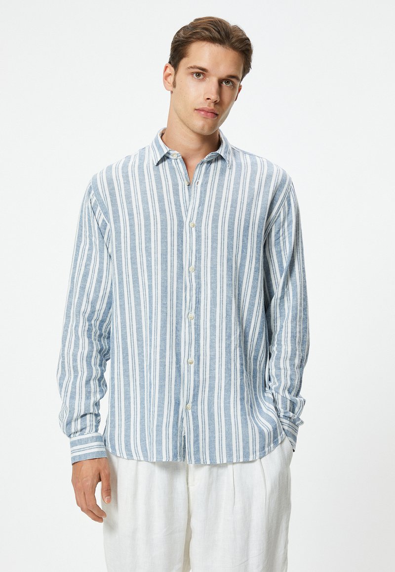 Camisa de manga larga con botones que presenta rayas verticales en azul y blanco, confeccionada en una tela ligera con cuello y un corte clásico.