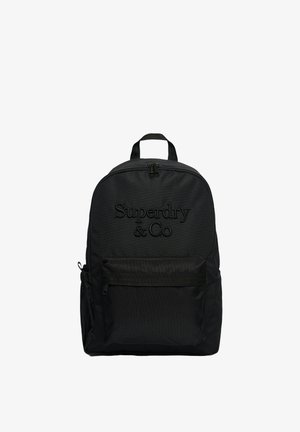Sort rygsæk med top lynlås, frontlomme, sidelomme og præget "Superdry & Co" logo på forsiden.