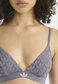 Světle fialová podprsenka ve tvaru trojúhelníku, s motivem listů, tenkými ramínky a logem uprostřed pásku.