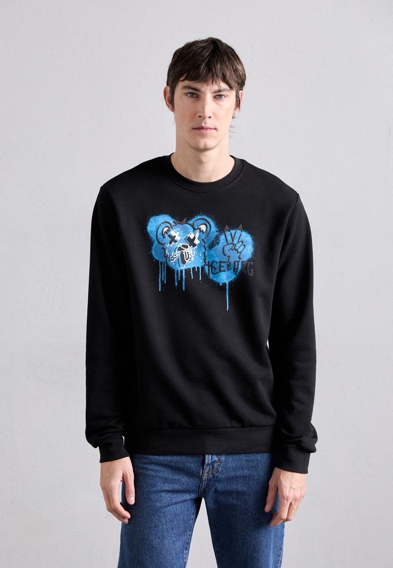 Sweatshirt noir avec un design graphique représentant un ours bleu et un symbole de paix. Fabriqué dans un matériau lisse avec une coupe décontractée et des poignets côtelés.