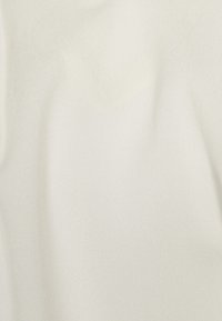 Vitt texturerat tyg med en mjuk, slät yta, som hänger mjukt utan synliga mönster eller detaljer. Perfekt för olika användningsområden.