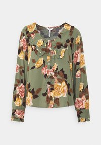 Blusa floreale verde con maniche lunghe, caratterizzata da un colletto arricciato e chiusura a bottoni. Rose gialle e rosa su un motivo di foglie scure.