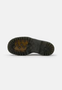 Sole in gomma con scanalature profonde e solide. Presenta una combinazione di texture marrone scuro e chiaro, con un design a motivo per una migliore aderenza.