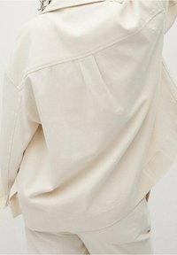 Crème-kleurige oversized jas van textuurstof, met een kraaghals, plooien op de rug en losse mouwen.
