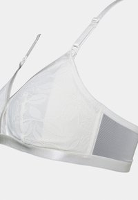 Sutiã branco de renda com um padrão floral, apresentando uma faixa de cetim lisa, alças ajustáveis e um detalhe em malha nas costas para maior conforto.
